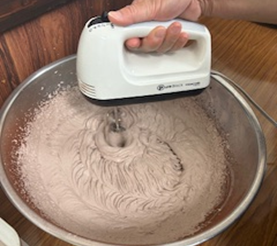 ボウルに入ったチョコレート生クリームをハンドミキサーで泡立てています。