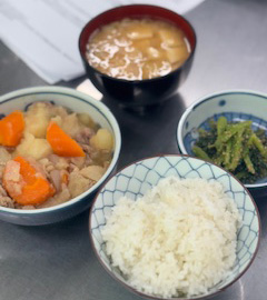 テーブルには、肉じゃが・味噌汁・ほうれん草の胡麻和え・ご飯が並べられています。