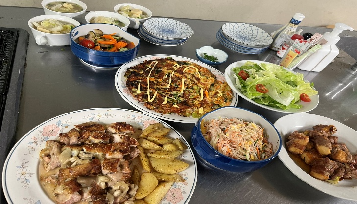 テーブルには、チキンとポテト・サラダ・角煮・お好み焼き風・スープ・小鉢などが並んでいます。