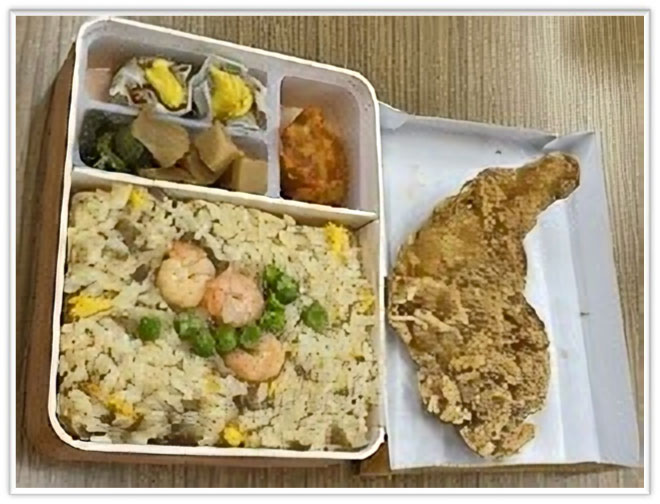 机の上に、崎陽軒の炒飯弁当とモスチキンが並べられている。