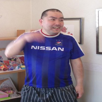 横浜F・マリノスのユニフォームを着て、ほかの参加者と話をする男性。