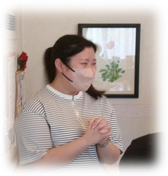 笑顔で手を組み、参加者の前で自己紹介をする女性。