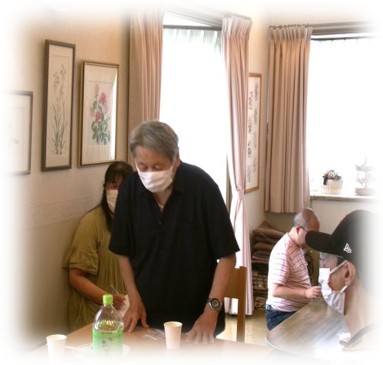 椅子から立ち上がり、参加者に向かって自己紹介をする男性。