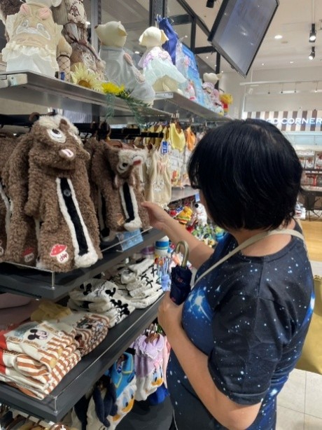 女性がペットショップで、ペット用の洋服を見ています。
